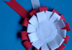 Kotylion wykonany z papieru, czyli koliste rozetki składające się z dwóch okręgów białego centralnego i czerwonego okalającego